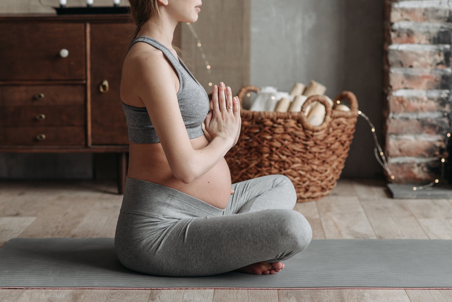 a pregnant woman wearing gray tank top meditating (consejos para reducir  flacidez y estrías)